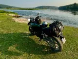 Motocykl z bagażem nad rzeką, gotowy do podróży po Litwie. Przepisy drogowe to podstawa bezpiecznej wyprawy.