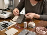 Tuto enveloppe rectangulaire : mains cousant un portefeuille en tissu, avec machine à coudre, ciseaux, épingles et ruban à mesurer.