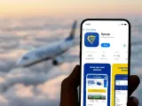 Ręka trzyma smartfon z aplikacją Ryanair, gotową do odprawy online. W tle leci samolot.