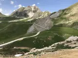Strada bianca serpeggia tra verdi colline e rocce, verso un monte imponente. Un'avventura in **moto** su una **colle fauniera** panoramica.