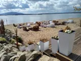 Plaża nad mietkowym zalewem z meblami z palet. W oddali góra i jezioro.