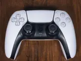 Biały kontroler DualSense do PS5 leży na drewnianym blacie. Zastanawiasz się nad ps4 pobór prądu?