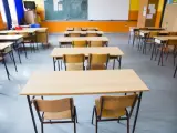 Pusta klasa szkolna z rzędami ławek i krzeseł. W tle tablica i okna. Obowiązek nauki czeka na uczniów.