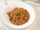 Arroz con sepia en un plato blanco, decorado con perejil.