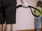 Chłopiec stoi w kącie za karę, a mężczyzna trzyma pas.