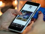 Kobieta z kartą kredytową w dłoni przegląda na smartfonie stronę e-commerce, ucząc się, jak sprzedawać bieliznę w internecie.