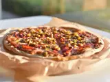 Apetyczna pizza Giuseppe 4 sery, z kukurydzą i mięsem, na papierze do pieczenia, w słonecznym świetle.