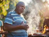Mężczyzna z bólem w klatce piersiowej przy grillu. Może szuka czegoś, co neutralizuje kwas żołądkowy po obfitym posiłku.