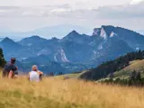 Para siedząca na trawiastym wzgórzu z widokiem na góry.