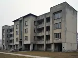 Szary blok mieszkalny z balkonami i dużymi oknami, typowy przykład architektury PRL.