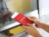 Ręce trzymają czerwony paszport z biletem lotniczym. Pamiętaj, czego nie wolno wywozić z Sycylii, by uniknąć problemów.