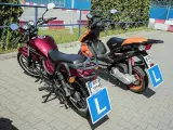 Dwa pojazdy, motocykl i skuter, z tabliczkami "L" na błotnikach, gotowe do nauki jazdy. Karta motorowerowa wkrótce będzie ich przepustką.