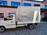 Biały samochód ciężarowy do 2,5 tony z plandeką gotowy do transportu towarów.