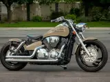 Beżowy motocykl Honda VTX 1300 z chromowanymi elementami i czarnym siedzeniem, zaparkowany na ulicy.