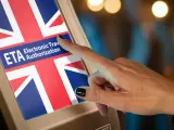 Palec dotyka ekranu z flagą Wielkiej Brytanii i napisem "ETA Electronic Travel Authorization". To krok do uzyskania wizy do Anglii.