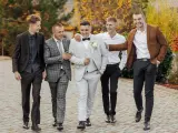 Pięciu mężczyzn w eleganckich stylizacjach, pokazujących, jakie są trendy w stylizacjach męskich dla gości weselnych 2026: garnitury, marynarki i klasyczne koszule.