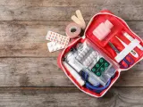 Trousse de secours pharmacie liste : pansements, rouleau de sparadrap, pilules, thermomètre, ciseaux, stéthoscope et masque.