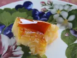 Un trozo de tocino de cielo de la abuela, con su caramelo brillante, sobre un plato decorado con flores y frutos.