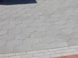 Szara, sześciokątna trelinka tworzy wzór na chodniku.