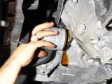 Wymiana filtr oleju co ile? Widać rękę z pierścionkiem odkręcającą stary filtr, z którego kapie olej.