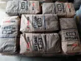 Sztaplowane worki z betonem B25, każdy po 25 kg. Wiedząc, ile waży kubik betonu, można oszacować potrzebną ilość materiału.