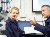 Młoda pracownica i starszy mężczyzna omawiają dokumentację techniczną. To część rutynowych badań okresowych pracowników.