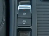 Przycisk AUTO HOLD w samochodzie. To funkcja, która automatycznie utrzymuje pojazd w miejscu po zatrzymaniu.