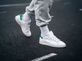 Un paio di sneakers bianche con dettagli verdi, simbolo di stile e comfort. Il loro significato va oltre la moda, rappresentando libertà di movimento.