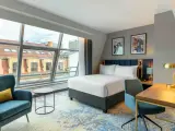 Nowoczesny pokój hotelowy z dużym oknem i widokiem na dachy. Czy zeby zarezerwowac hotel ttzna miec 18 lat? Tak, zazwyczaj.