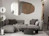 Nowoczesny salon z szarą sofą, geometrycznym lustrem i designerską lampą.