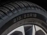 Opona samochodowa z oznaczeniem 215/55R18. Widoczny bieżnik i felga. Indeks prędkości jest kluczowy dla bezpieczeństwa.
