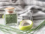 A jar filled with dried chives, showcasing how to dry chives for long-term storage. Fresh chives and kitchen tools are nearby.