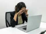 Femme stressée devant son ordinateur, les mains sur les tempes. Une situation difficile, peut-être un licenciement pendant arrêt maladie pour dépression.