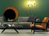 Elegante soggiorno con divano grigio, poltrona in pelle color cuoio e specchio rotondo. Idee su come abbinare divano e poltrone diverse.