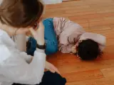 Mama próbuje zrozumieć, jak zapanować nad złością na dziecko, które leży na podłodze, ukrywając twarz.