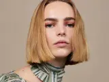 Blond włosy z przedziałkiem na bok, delikatny makijaż oczu i ust, zielony wzorzysty szal.