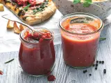 Dwa słoiki z domowym sosem do pizzy. Jeden otwarty, z łyżką pełną sosu, gotowy do użycia.