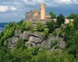 Zamek Chojnik, majestatyczna twierdza na skalistym wzgórzu, otoczona bujną zielenią.
