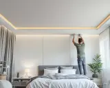Installazione di pannelli per l'isolamento acustico del soffitto in una camera da letto moderna.