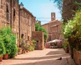 Un borgo medievale con case in pietra, fiori colorati e un gatto nero che riposa al sole. Un'idea per scoprire i paesi vicino a Grosseto da visitare.