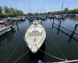 Un voilier blanc, type Westerly Centaur, est amarré dans un port. D'autres bateaux sont visibles au loin.