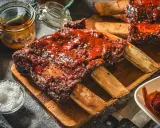 Saftige Rippchen mit BBQ-Sauce, perfekt für Ihre nächsten Grill Rezepte. Dazu grobes Salz und eine Schüssel Sauce.