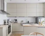 Beżowa kuchnia inspiracje: minimalistyczne szafki, drewniany blat, stalowy okap i eleganckie dodatki tworzą przytulną atmosferę.