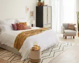 Cama acogedora con manta ocre y cojines vibrantes, ideal para un ambiente de feng shui cama.