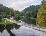 Idealna wycieczka na niedzielę na Dolny Śląsk: nowoczesny most nad spokojną rzeką, otoczony jesiennym lasem i wieżą widokową na wzgórzu.