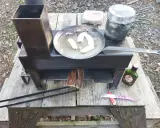 Poêle rocket fait maison, avec des bananes qui dorent dans une poêle, une marmite et une bouteille de rhum Negrita.