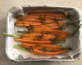 Carote al forno, tagliate a metà, condite con rosmarino e semi di sesamo, pronte per essere infornate.