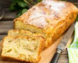 Szybkie ciasto z jabłkami, posypane cukrem pudrem, pokrojone na kromki, leży na desce obok jabłek i noża.