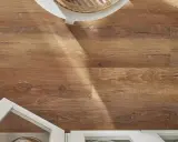 Drewnopodobne panele laminowane czy winylowe na podłodze, z fragmentem białej szafki i blatu.