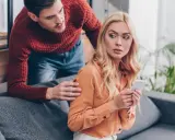 Chorobliwa zazdrość mężczyzny. Patrzy na telefon partnerki, która wygląda na zaniepokojoną.